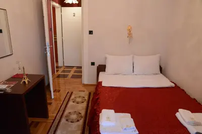 a small room with a bed with a red blanket at Apartmani Vivaldi Niš in Niš