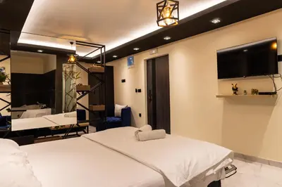 a bedroom with a white bed and a flat screen tv at Guest House Vila Salute in Niš