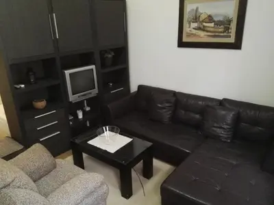 a living room with a black leather couch and a coffee table at Guest House Amico in Vranje
