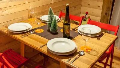 a wooden table with white plates and a bottle of wine at Šum Apartmani - Stara planina in Crni Vrh