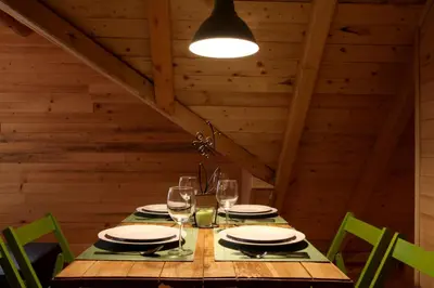 a wooden table with plates and wine glasses at Šum Apartmani - Stara planina in Crni Vrh
