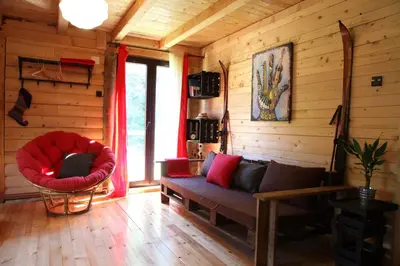 a living room with a couch and a red chair at Šum Apartmani - Stara planina in Crni Vrh
