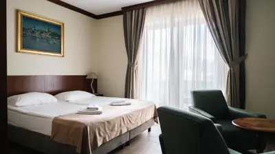 a hotel room with a bed and chairs and a window at Hotel Vila San in Kopaonik