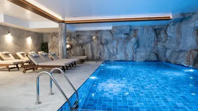 a pool in a room with a rock wall at Hotel Vila San in Kopaonik