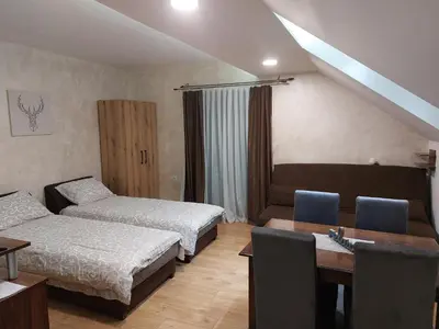 a hotel room with two beds and a table and a desk at Apartments Vila Djurdja in Kopaonik