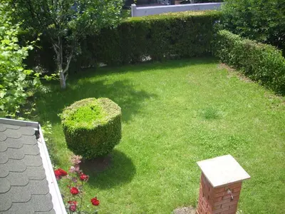 a yard with a hedge and a lawn with flowers at Guest House Nada in Soko Banja