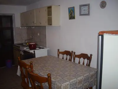 a kitchen with a table and chairs and a kitchen with a refrigerator at Guest House Nada in Soko Banja