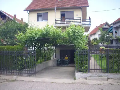 a man sitting at a table in front of a house at Guest House Nada in Soko Banja
