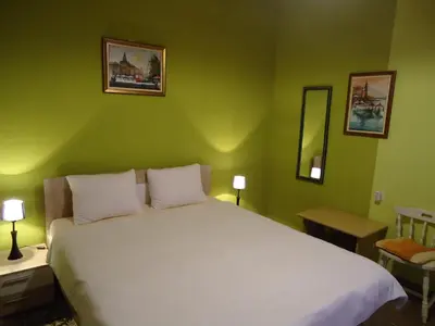 a bedroom with a large white bed with green walls at Apartments Villa Svetlana in Vrnjačka Banja