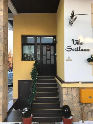 a yellow building with a black door and stairs at Apartments Villa Svetlana in Vrnjačka Banja