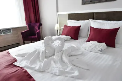 a bed with white sheets and red pillows at Hotel Ana Lux Spa in Pirot