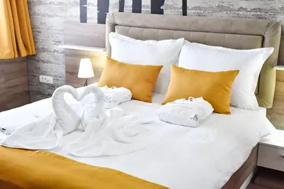 a bed with white blankets and pillows on it at Hotel Ana Lux Spa in Pirot