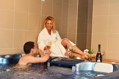 a woman sitting in a tub with a man holding a glass of wine at Hotel Ana Lux Spa in Pirot