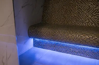 a bench in a bathroom with a blue light at Hotel Bella Nella in Leskovac