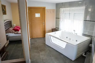 a bathroom with a white tub and a bedroom at Hotel Bella Nella in Leskovac