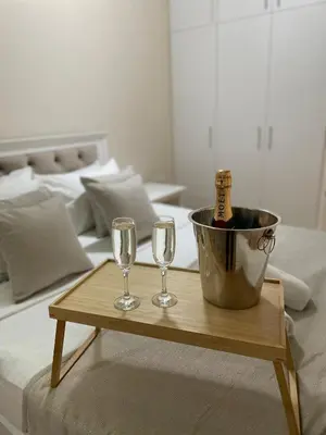 a table with two wine glasses and a bucket on a bed at Hotel Bella Nella in Leskovac