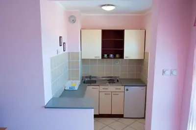 a kitchen with pink walls and white cabinets and a sink at Apartments Kaskade in Soko Banja