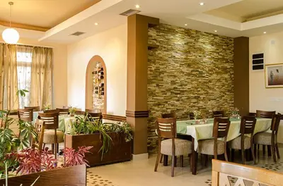 a restaurant with a table and chairs and a stone wall at Apartments Kaskade in Soko Banja