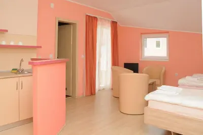 a room with pink walls and a kitchen with a bed at Apartments Kaskade in Soko Banja