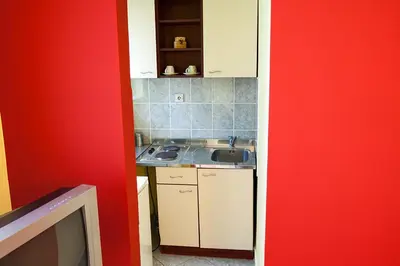 a kitchen with a sink and a red wall at Apartments Kaskade in Soko Banja