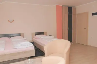 a hotel room with two beds and a chair at Apartments Kaskade in Soko Banja