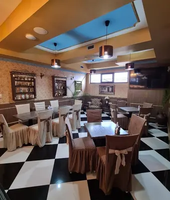 a restaurant with tables and chairs on a checkered floor at Garni Hotel & Spa Nicolo in Kruševac