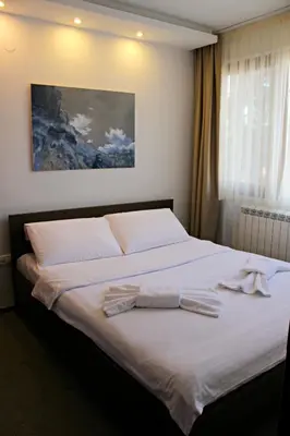 a bedroom with a large white bed with towels on it at Hotel Happy in Dimitrovgrad