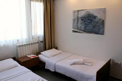 a hotel room with two beds and a painting on the wall at Hotel Happy in Dimitrovgrad
