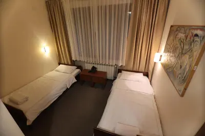a hotel room with two beds and a table at Hotel Happy in Dimitrovgrad