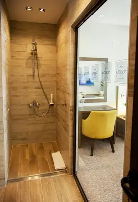 a bathroom with a shower and a yellow chair at Hotel Happy in Dimitrovgrad
