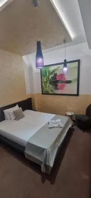 a bedroom with a bed with two lights and a painting at Garni Hotel Zen free parking in Niš