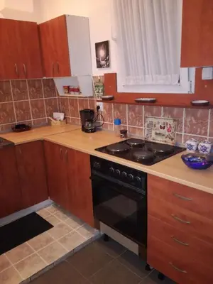 a kitchen with wooden cabinets and a black stove top oven at Apartman Centar in Kruševac