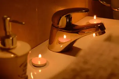 two candles sitting on a bathroom sink with a faucet at Love Apartment in Vrnjačka Banja