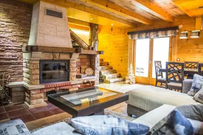 a living room with a stone fireplace in a log cabin at Holiday Home Floris in Kopaonik