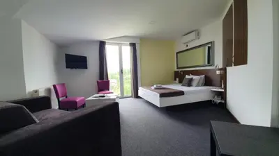 a hotel room with a bed and a couch at Garni Hotel Niš City View & Spa in Niš