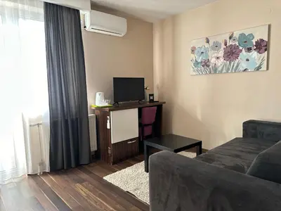 a living room with a couch and a tv at Garni Hotel Niš City View & Spa in Niš