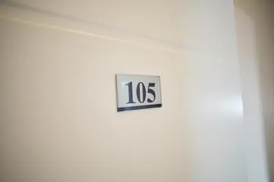 a clock on the side of a white wall at Lotos Depandans in Niš