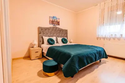 a bedroom with a large bed with a green blanket at Lotos Depandans in Niš