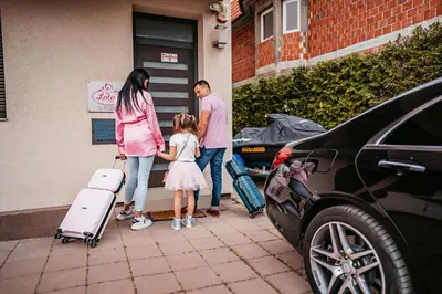 a family standing next to a car with their luggage at Lotos Depandans in Niš