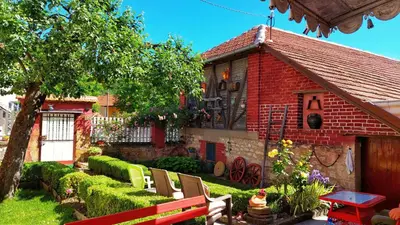 a red brick house with a bench in front of it at Vila Milenovic Rajacke Pivnice in Rajac