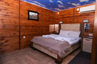 a bedroom with a bed in a wooden wall at Cuki Residence in Mala Ravna Reka