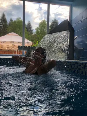 a woman in a swimming pool with a water fountain at Cuki Residence in Mala Ravna Reka