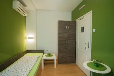a green room with a bed and a sink at Sweet Apartments or Rooms in Niš