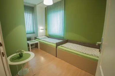 a small room with two beds and a table at Sweet Apartments or Rooms in Niš