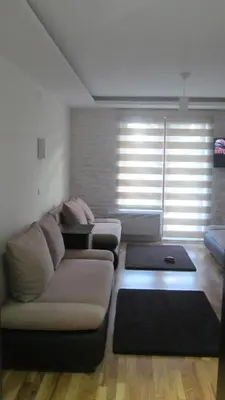 a living room with a couch and a large window at Apartments Vanja i Vrh in Kopaonik