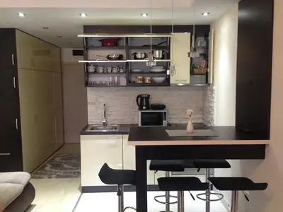 a kitchen with a counter and some black chairs at Apartments Vanja i Vrh in Kopaonik