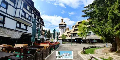 a city street with tables and a clock tower at Apartments KOP Konaci in Kopaonik