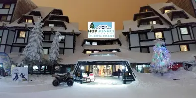 a snow covered building with a christmas tree in front of it at Apartments KOP Konaci in Kopaonik