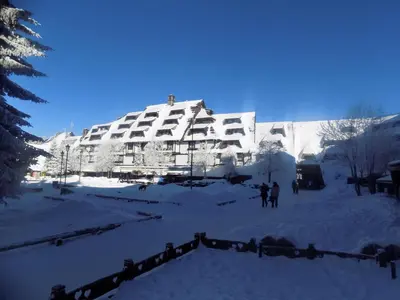 a snow covered building with people standing in front of it at Apartment Sofia-Konaci in Kopaonik