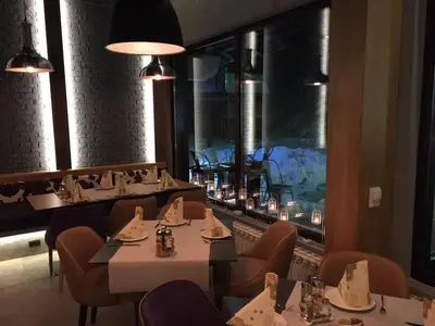 a restaurant with tables and chairs and a large window at Apartment Sofia-Konaci in Kopaonik